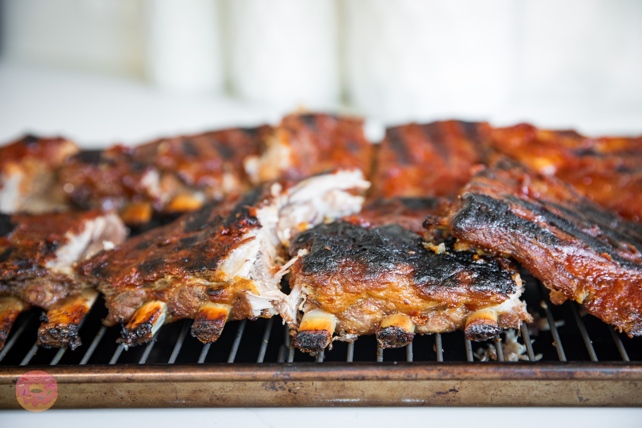 Close-up of tender oven-baked ribs with smoky dry rub and glossy BBQ sauce, showing juicy meat falling off the bone