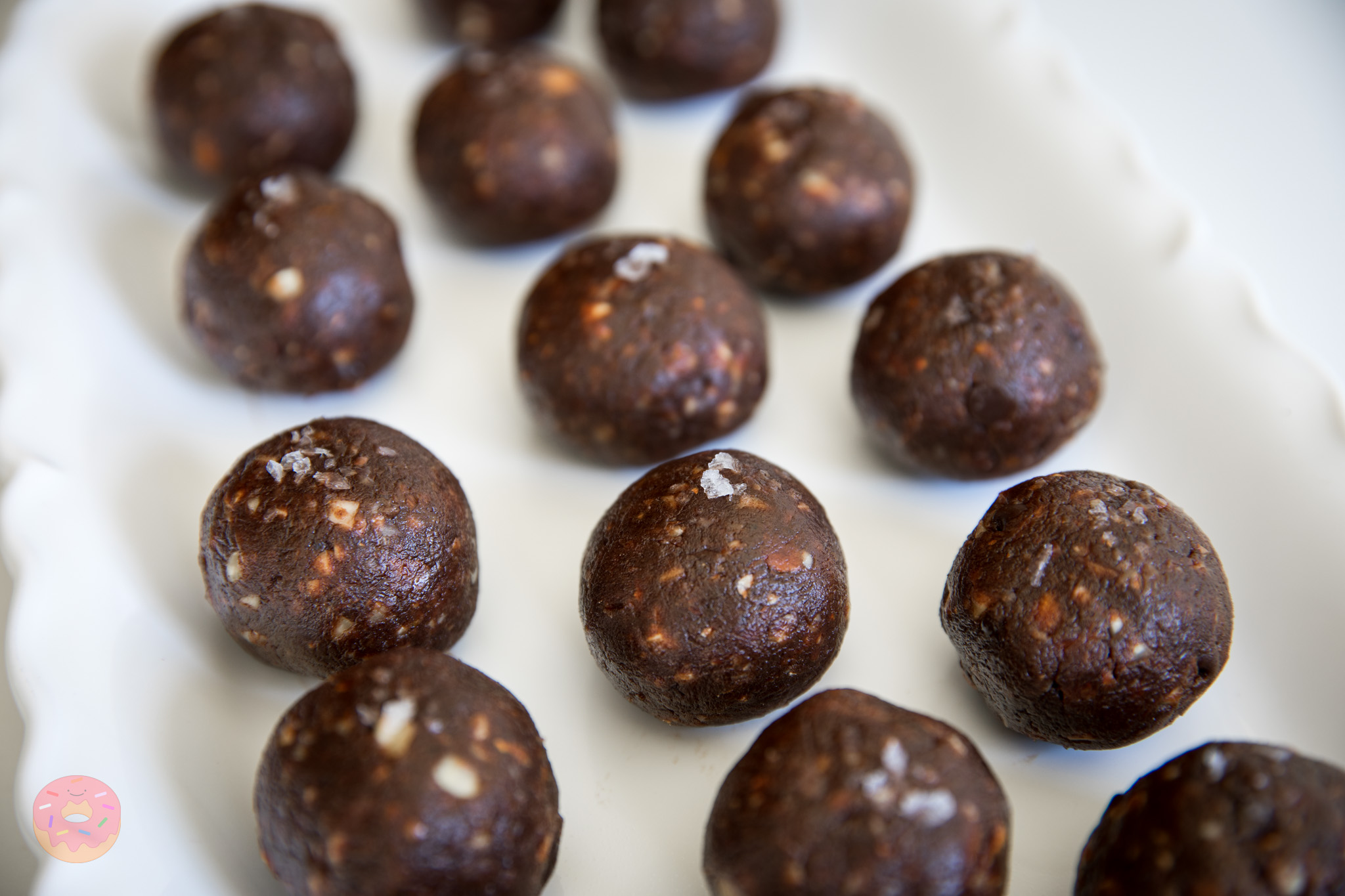 Close-up of rich chocolate date balls made with almonds and hazelnuts, showing chewy texture and crunchy nut pieces, healthy no-sugar snack