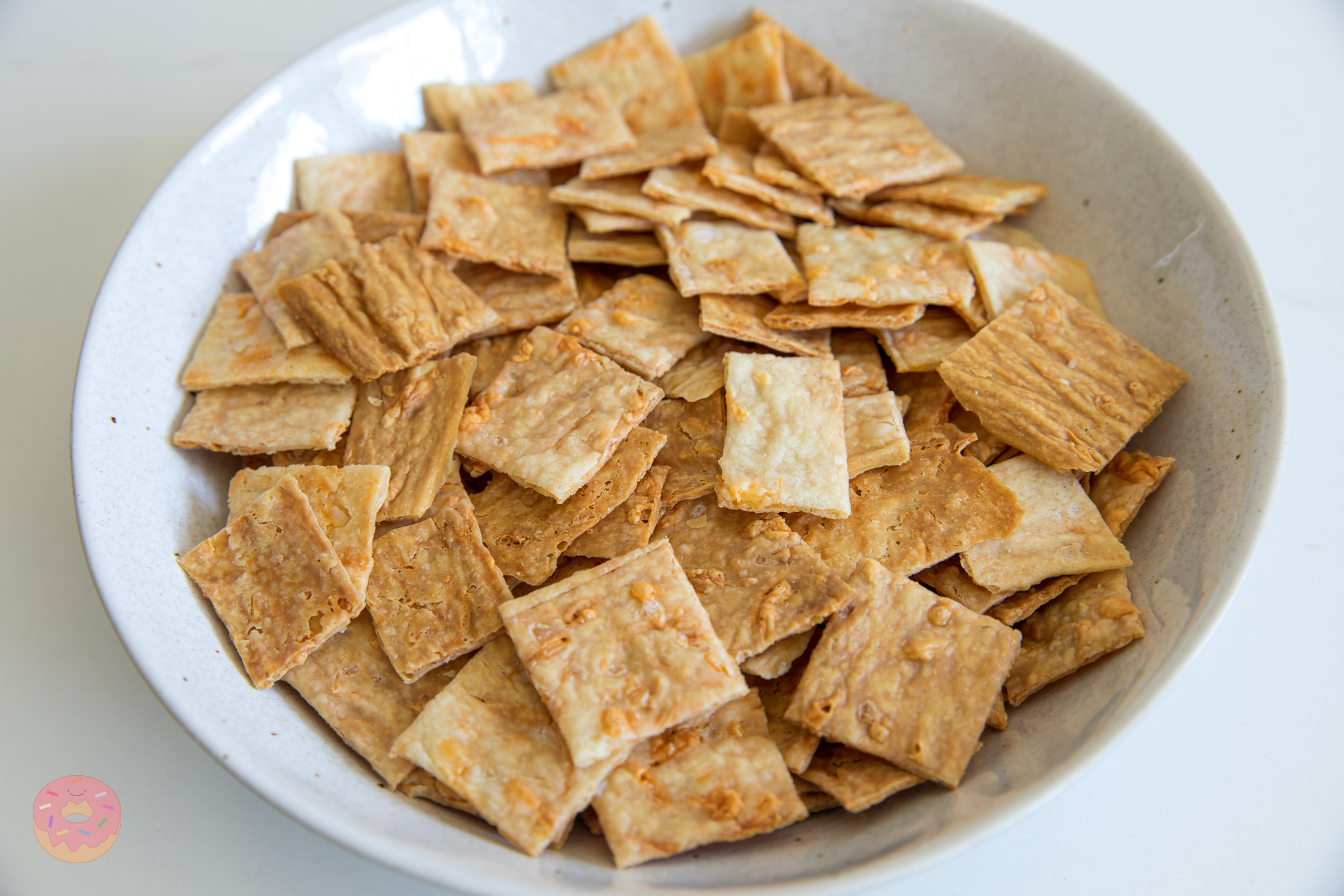 Thin and crunchy sourdough discard crackers in a bowl, showing their golden color and flaky texture.